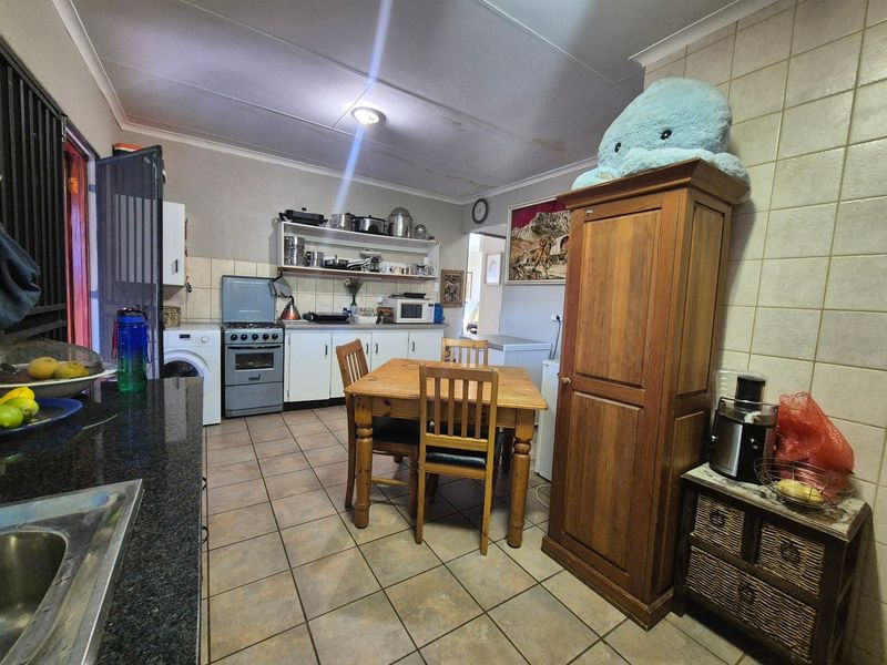 Kitchen featuring tiled flooring, granite countertops, and built-in cabinetry. The space includes a dedicated dining area and requires some ceiling maintenance.