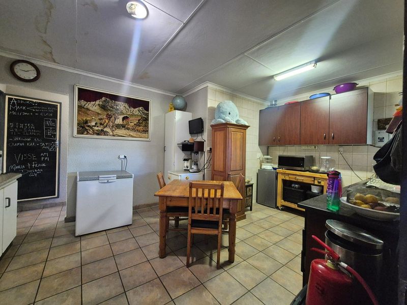 A functional kitchen space featuring tiled flooring, built-in cabinetry, and a tiled backsplash, currently showing signs of wear and ceiling water damage.