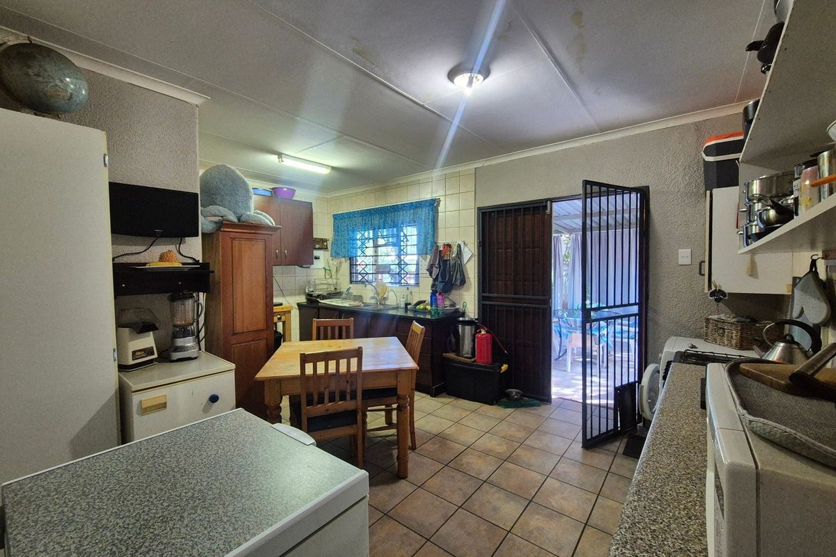 A functional kitchen area featuring tiled floors, laminate countertops, and direct access to an outdoor patio through a security gate.
