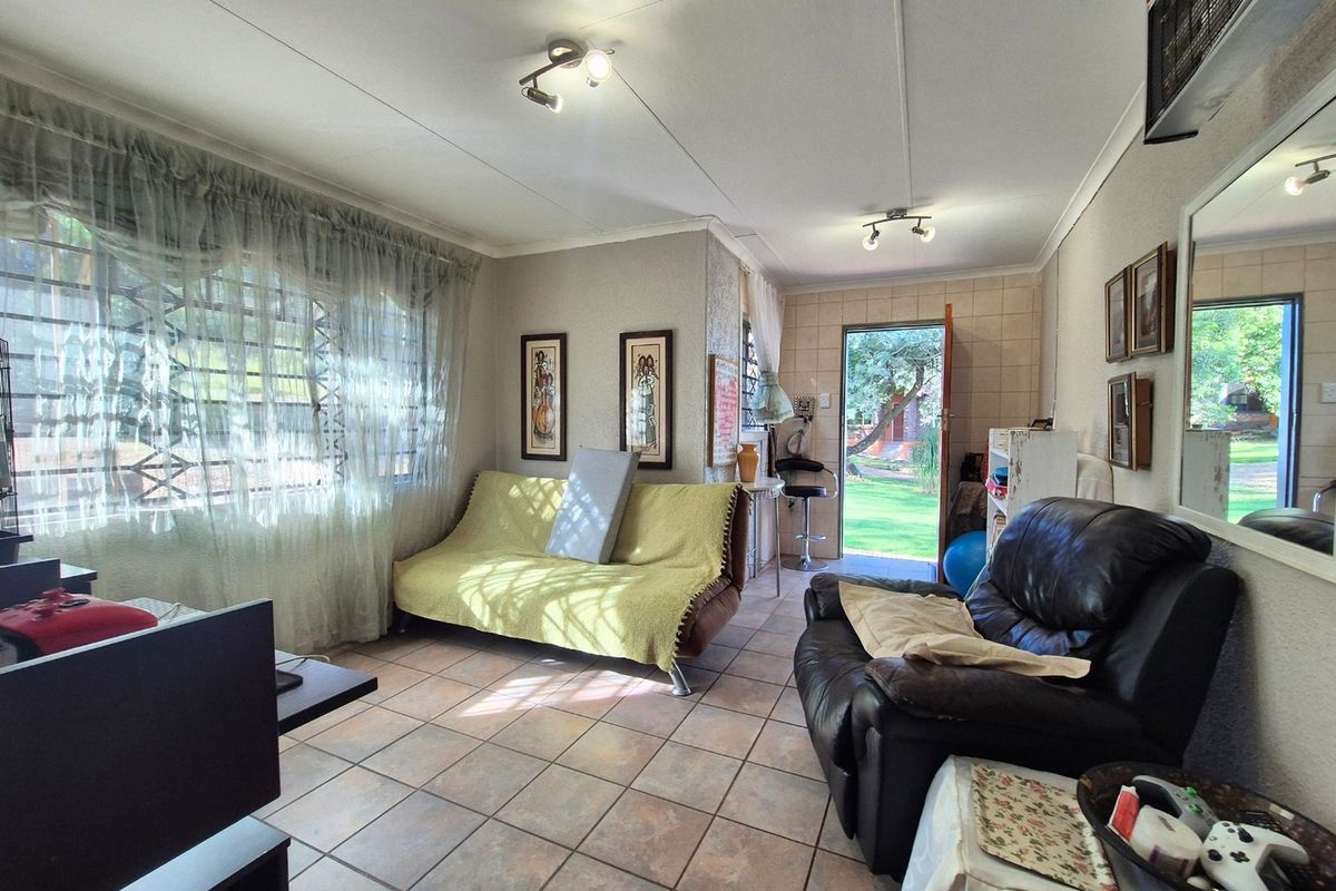 A living room featuring tiled flooring, security bars on the windows, and direct access to the garden area.