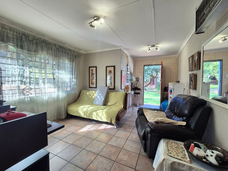 A living room featuring tiled flooring, security bars on the windows, and direct access to the garden area.