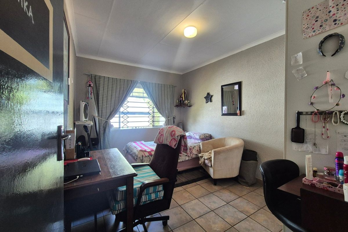 A functional bedroom featuring tiled flooring, a window with security bars, and a standard ceiling light fixture.