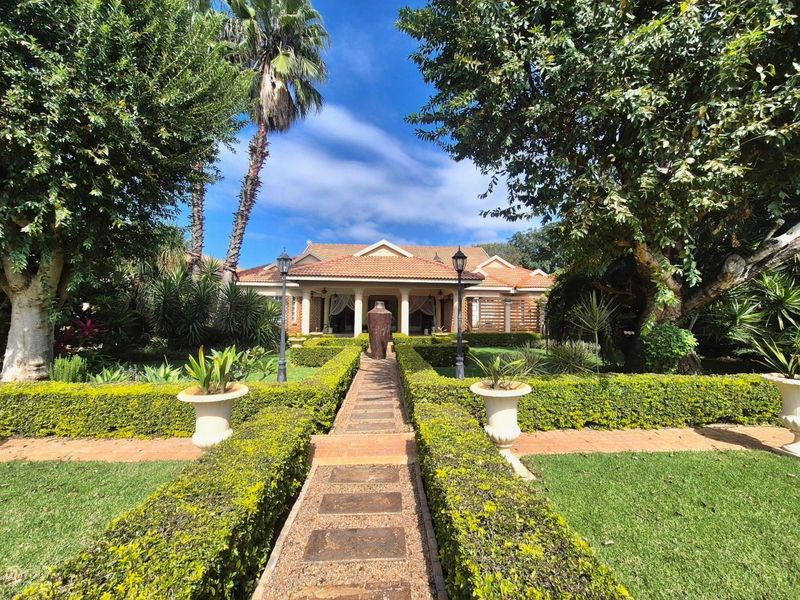 A well-maintained front facade featuring a symmetrical design, a paved walkway leading to a covered entrance, and established landscaped gardens.