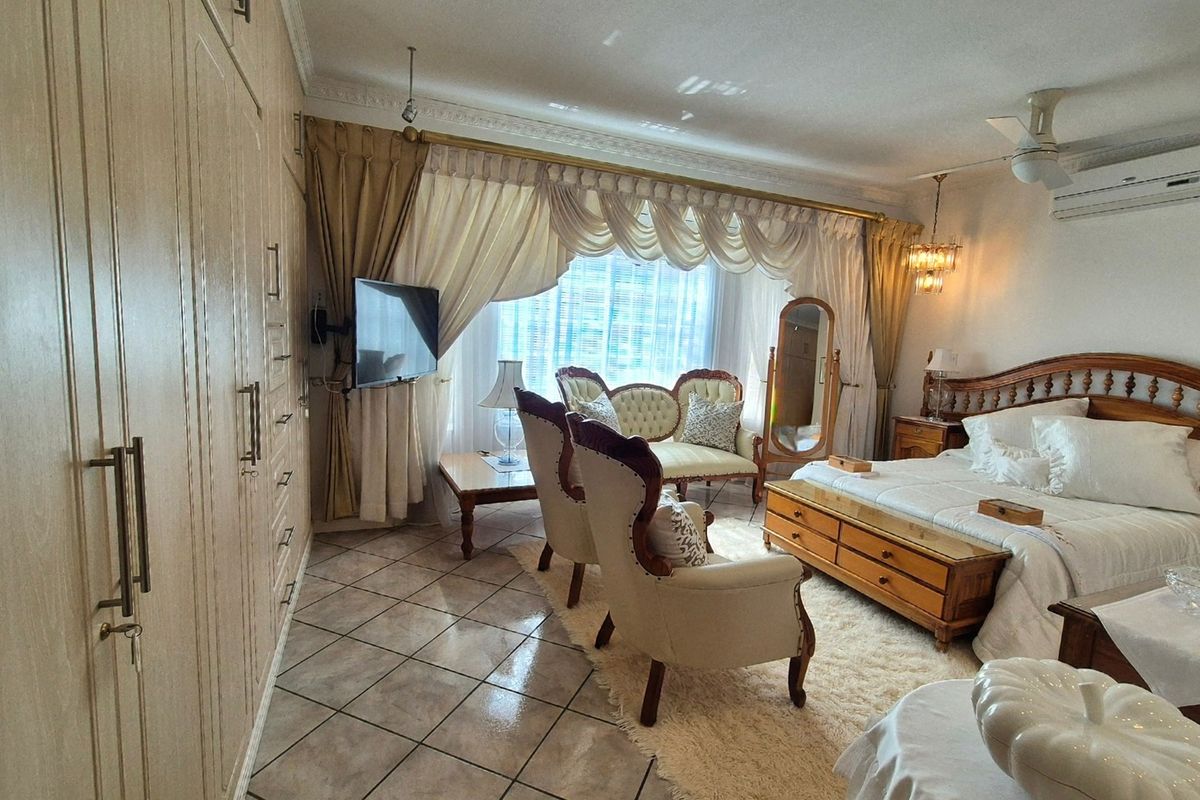 Spacious bedroom featuring extensive built-in cabinetry, tiled flooring, crown molding, and integrated climate control with a ceiling fan and air conditioning unit.