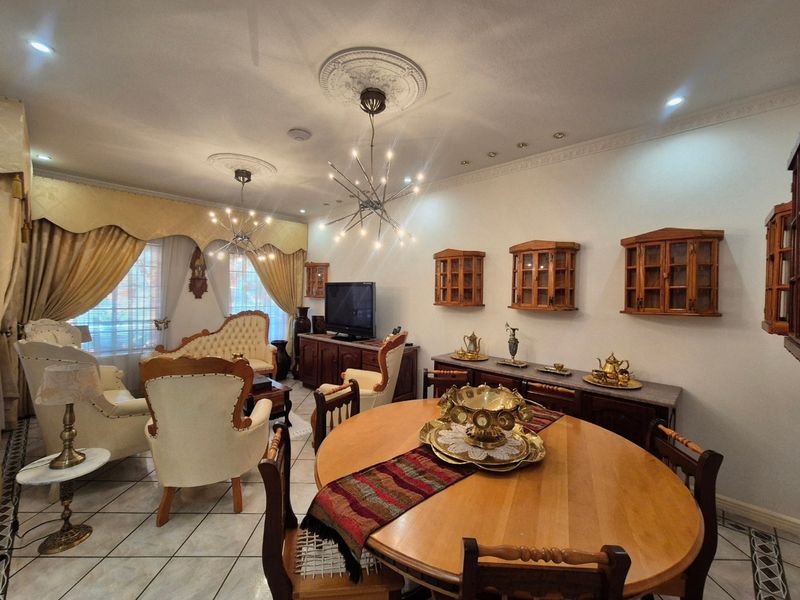 Spacious open-plan living and dining area featuring decorative ceiling roses, crown molding, tiled flooring, and built-in wall cabinetry.