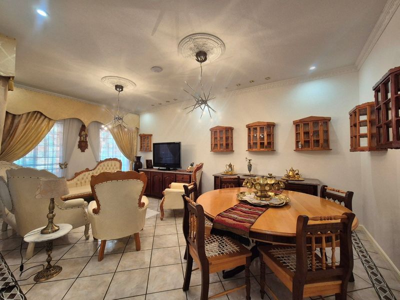 Spacious open-plan living and dining area featuring ceramic tiled flooring, decorative ceiling roses, and built-in wall-mounted display cabinetry.