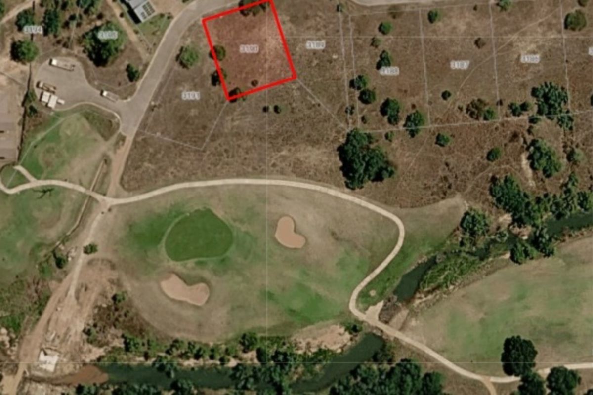 Aerial view of a vacant residential land plot situated in a golf estate, highlighting the property boundaries and surrounding landscape.