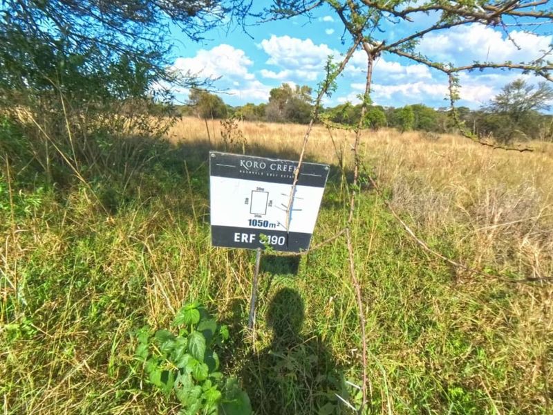 A view of a vacant residential plot of land measuring 1050 square meters, featuring natural vegetation and a property identification sign.