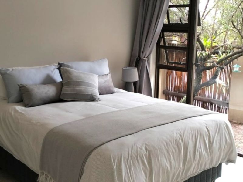 A well-lit bedroom featuring a large sliding glass door that provides direct access to the outdoor garden area.
