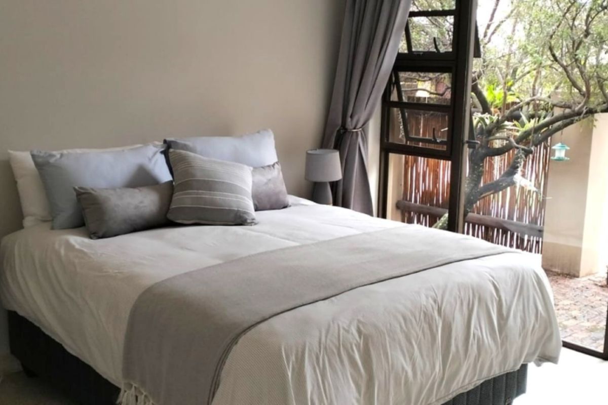 A well-lit bedroom featuring a large sliding glass door that provides direct access to the outdoor garden area.