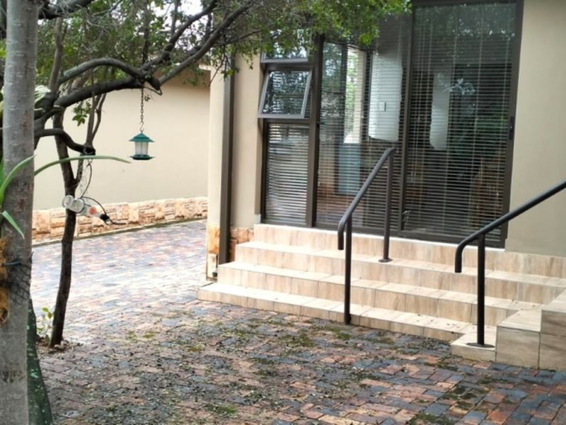 Rear exterior view featuring a brick paved patio area with tiled steps, metal handrails, and sliding glass door access to the home.