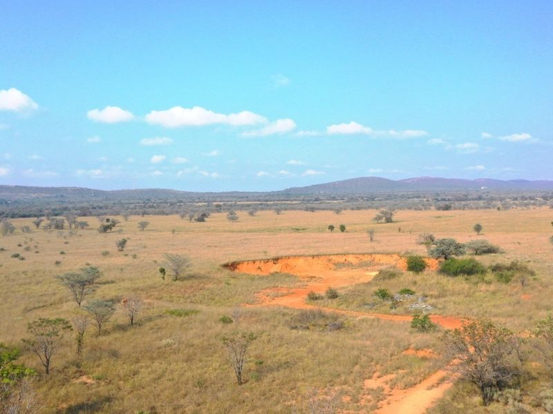 An expansive aerial view of the farm landscape featuring open grasslands, scattered trees, and natural terrain.