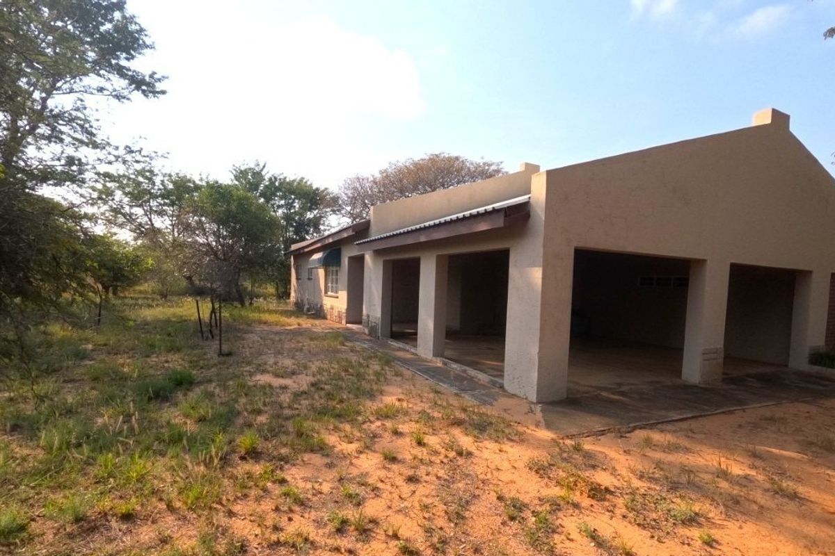 Rear view of the farm property featuring a covered patio area with concrete flooring and a stucco exterior finish.