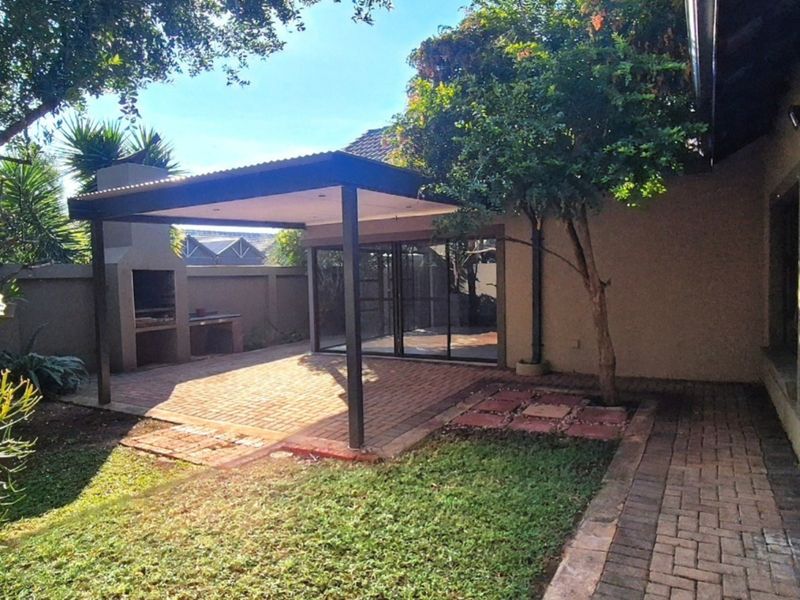 A covered outdoor patio area featuring a built-in braai, paved flooring, and direct access to the home through sliding glass doors.