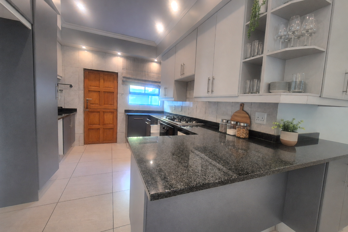 Modern kitchen featuring dark grey cabinetry, granite countertops, a gas hob, and tiled flooring with ample storage and open shelving.