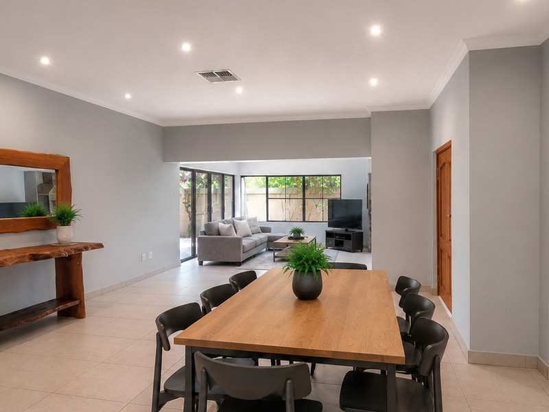 Spacious open-plan living and dining area featuring neutral tiled flooring, recessed downlighting, and large sliding glass doors providing access to the outdoor space.