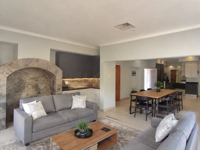 Spacious open-plan living and dining area featuring modern cabinetry, a unique stone-clad feature arch, and neutral tiled flooring throughout.