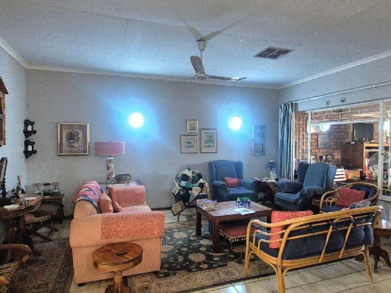 A spacious living room featuring tiled flooring, a ceiling fan, and a sliding glass door leading to an adjacent area.