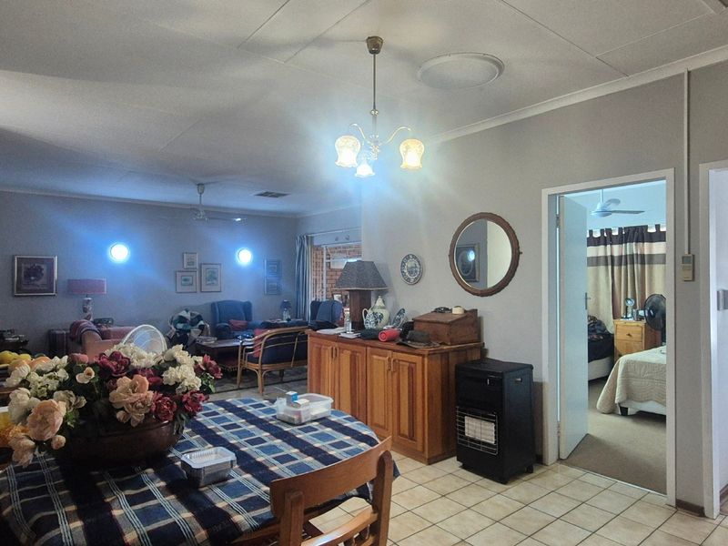 Open plan living and dining area featuring tiled flooring, coved ceilings, and access to adjacent bedrooms.