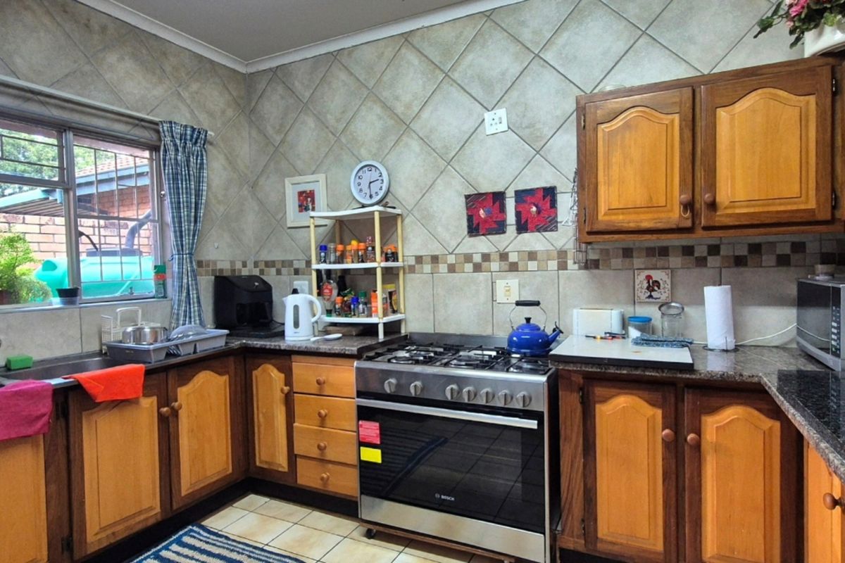A functional kitchen featuring wooden cabinetry, granite countertops, a gas stove with oven, and tiled backsplash finishes.