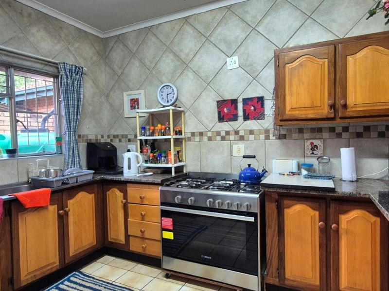 A functional kitchen featuring wooden cabinetry, granite countertops, a gas stove with oven, and tiled backsplash finishes.