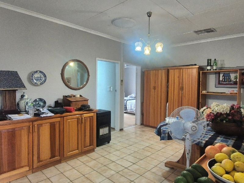 A living area featuring tiled flooring, built-in wooden cabinetry, and a central ceiling light fixture, offering a functional space with potential for modernization.