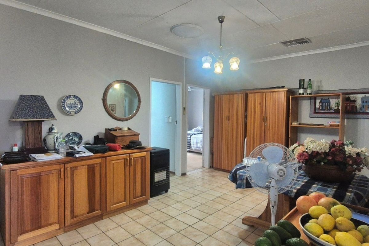 A living area featuring tiled flooring, built-in wooden cabinetry, and a central ceiling light fixture, offering a functional space with potential for modernization.