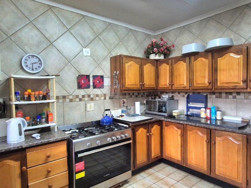 A functional kitchen featuring wooden cabinetry, granite countertops, a gas stove, and tiled backsplash, offering a classic layout with ample storage space.