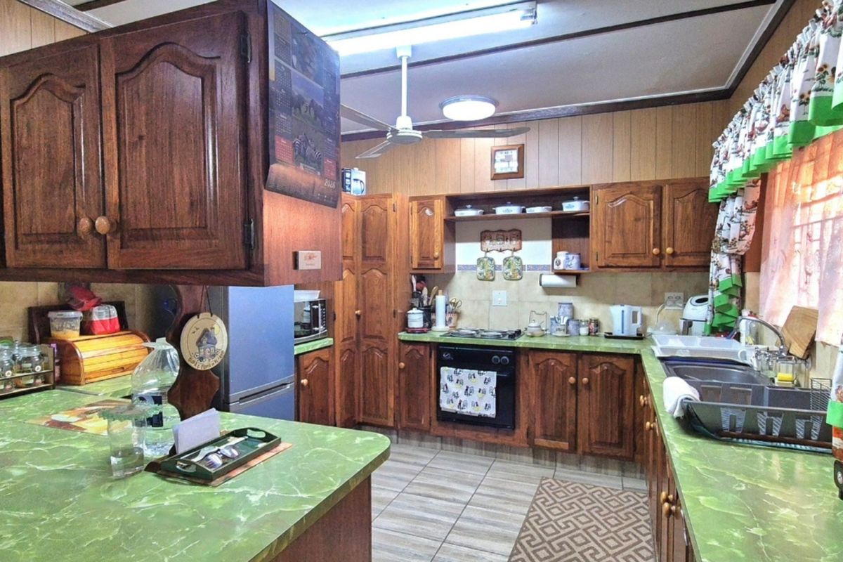 A traditional kitchen featuring extensive wooden cabinetry, laminate countertops, a built-in oven, and a functional layout with tiled flooring and backsplash.
