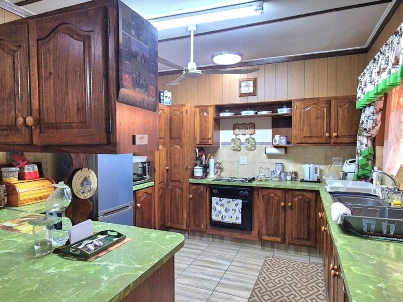 A traditional kitchen featuring extensive wooden cabinetry, laminate countertops, a built-in oven, and a functional layout with tiled flooring and backsplash.