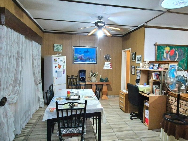 Dining area featuring tiled flooring, wood paneling, and a ceiling fan, offering a dated aesthetic with potential for modernization.