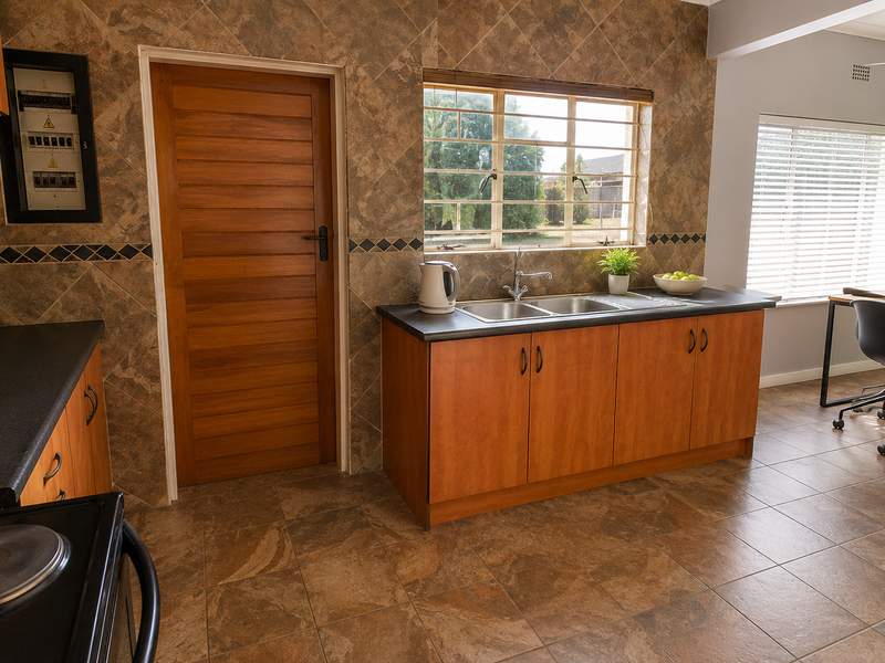 Open-plan kitchen and dining area featuring tiled flooring, built-in wooden cabinetry, a double sink, and an electric stove with a tiled splashback.