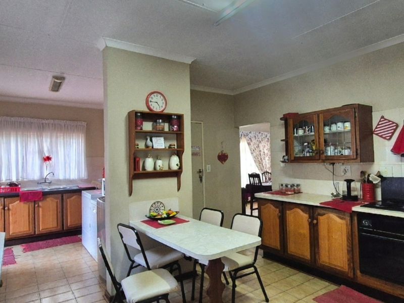 A functional kitchen featuring traditional wooden cabinetry, laminate countertops, built-in oven, and hob, with a practical layout and tiled flooring throughout.