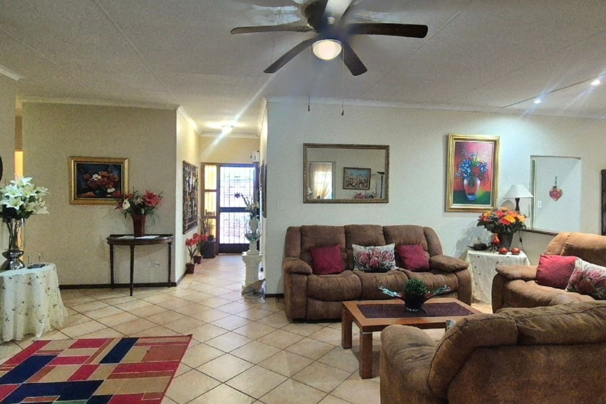 Spacious living room featuring tiled flooring, a ceiling fan, and an open-plan layout leading to the entrance area.