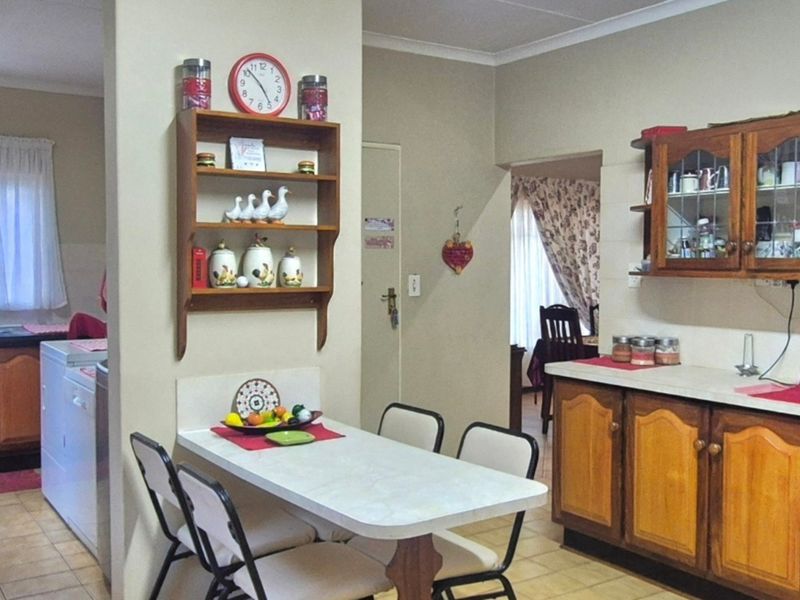 A functional kitchen featuring traditional wooden cabinetry, laminate countertops, and tiled flooring, with an integrated oven and a dedicated breakfast nook area.