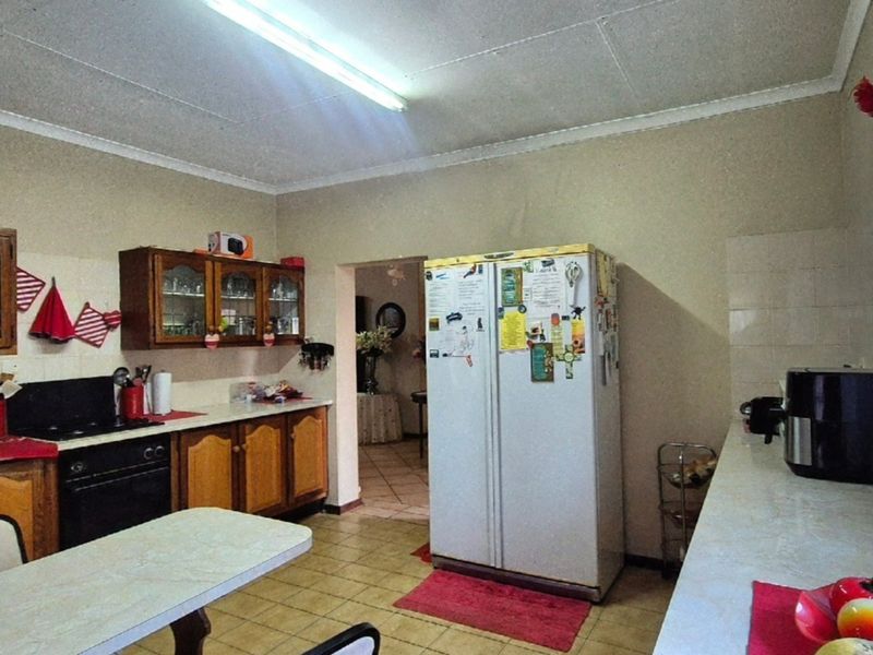 A dated kitchen featuring traditional wooden cabinetry, laminate countertops, and built-in cooking appliances, offering potential for a modern renovation.
