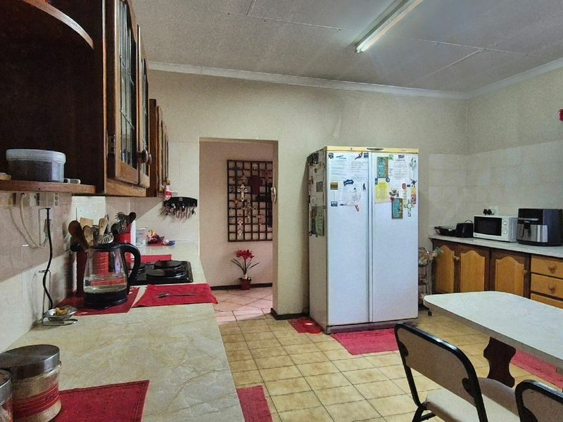 A functional kitchen featuring traditional wooden cabinetry, tiled flooring, and ample counter space, offering potential for a modern renovation.