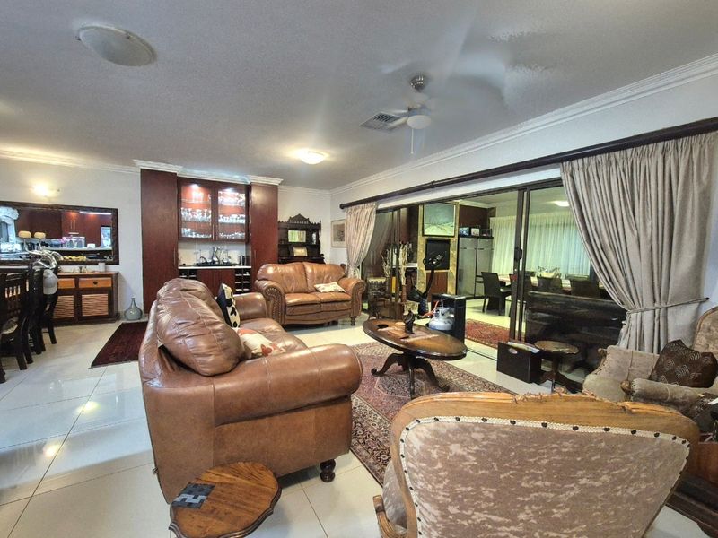 Spacious open-plan living area featuring tiled floors, built-in display cabinetry, and large sliding glass doors leading to an adjacent room.