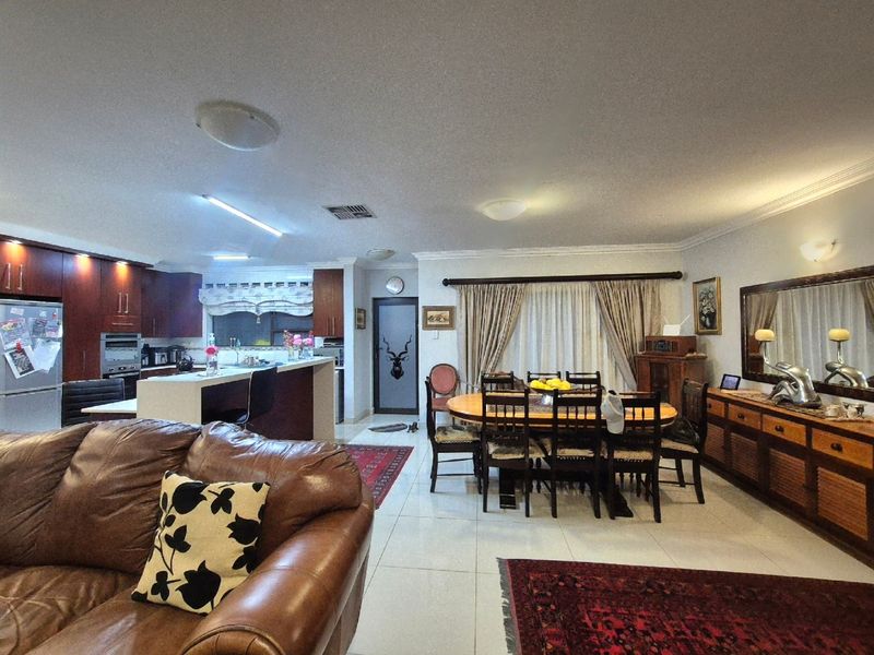 Spacious open-plan living and dining area featuring a modern kitchen with built-in cabinetry, a central island, and tiled flooring throughout.