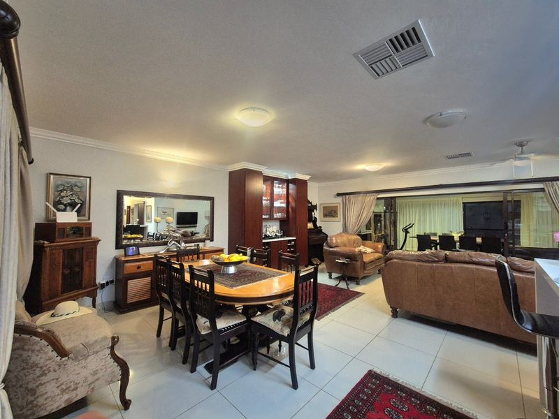Spacious open-plan living and dining area featuring tiled flooring, built-in cabinetry, and large sliding glass doors leading to an outdoor space.