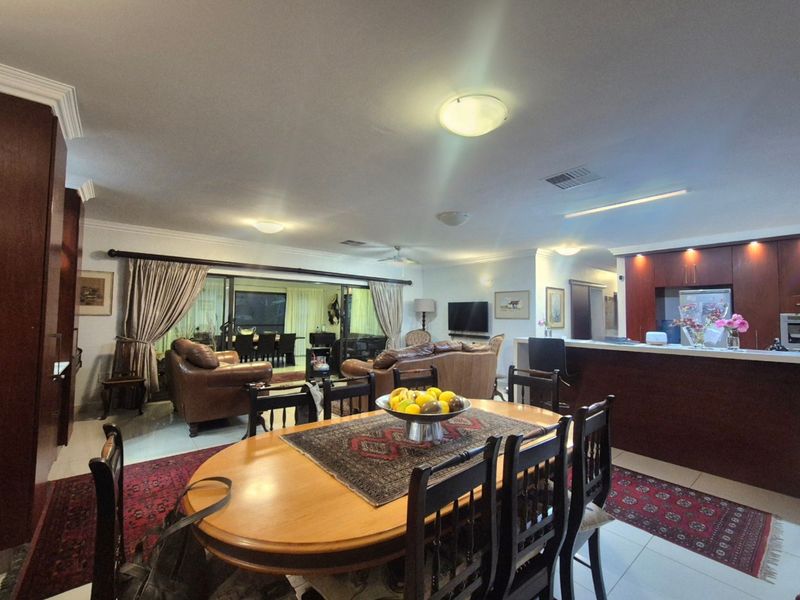 Spacious open-plan living, dining, and kitchen area featuring tiled floors, built-in cabinetry, and large sliding doors leading to an outdoor space.
