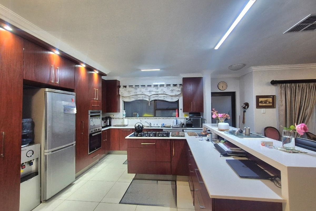 Spacious kitchen featuring dark wood cabinetry, stone countertops, a central gas hob, and a breakfast bar, offering ample storage and workspace.