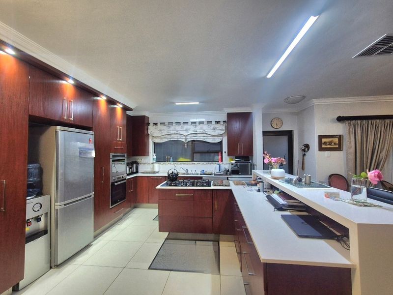 Spacious kitchen featuring dark wood cabinetry, stone countertops, a central gas hob, and a breakfast bar, offering ample storage and workspace.