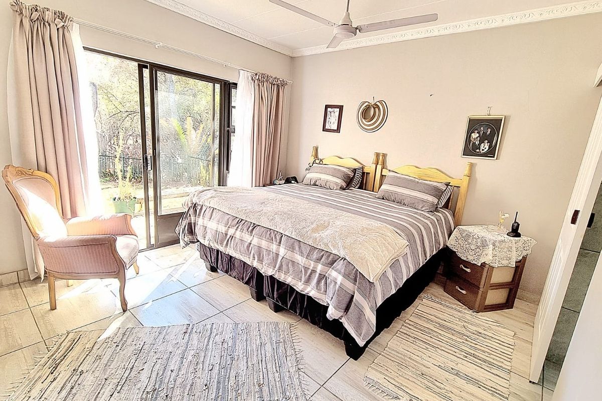 A bedroom featuring tiled flooring, a ceiling fan, and a sliding glass door providing direct access to the outdoor area.
