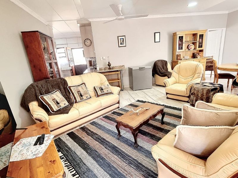 Spacious living room featuring tiled flooring, ceiling fan, and decorative coving, offering a comfortable and functional layout for relaxation.
