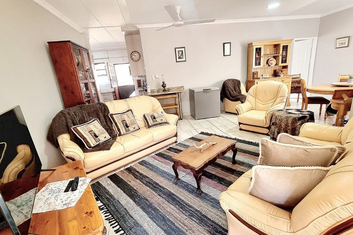 Spacious living room featuring tiled flooring, ceiling fan, and decorative coving, offering a comfortable and functional layout for relaxation.