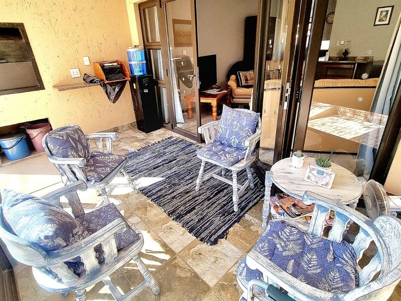 Covered patio area featuring a built-in braai, tiled flooring, and sliding glass doors providing access to the interior living space.