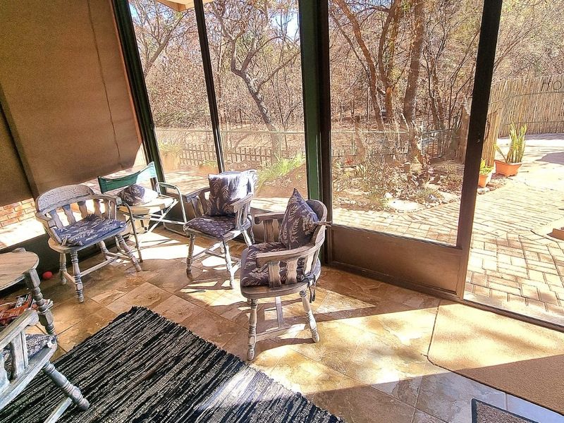 A bright, enclosed patio area featuring tiled flooring and large sliding glass doors that open onto a paved outdoor space.