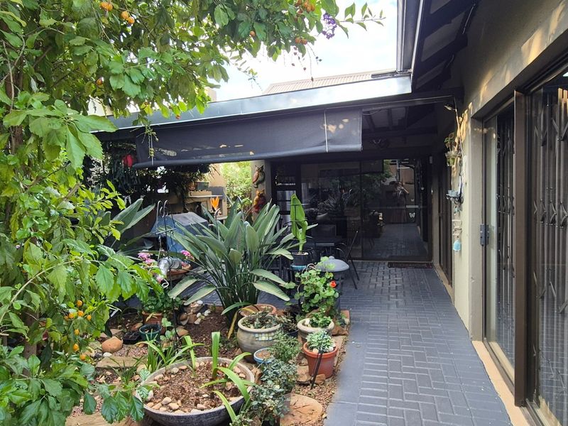 A covered patio area featuring paved flooring, a retractable awning, and direct access to the home through sliding glass doors.