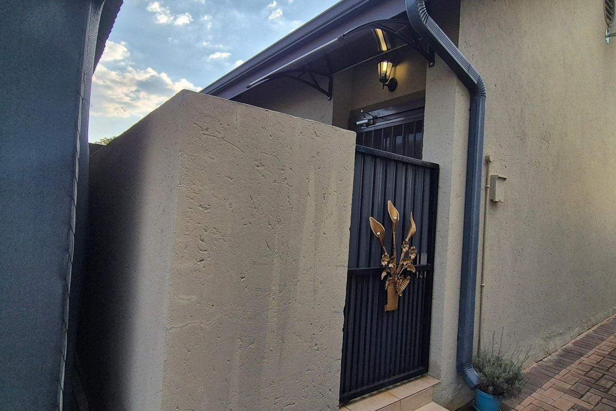A side access path featuring a secure metal gate, exterior lighting, and paved flooring along the side of the property.
